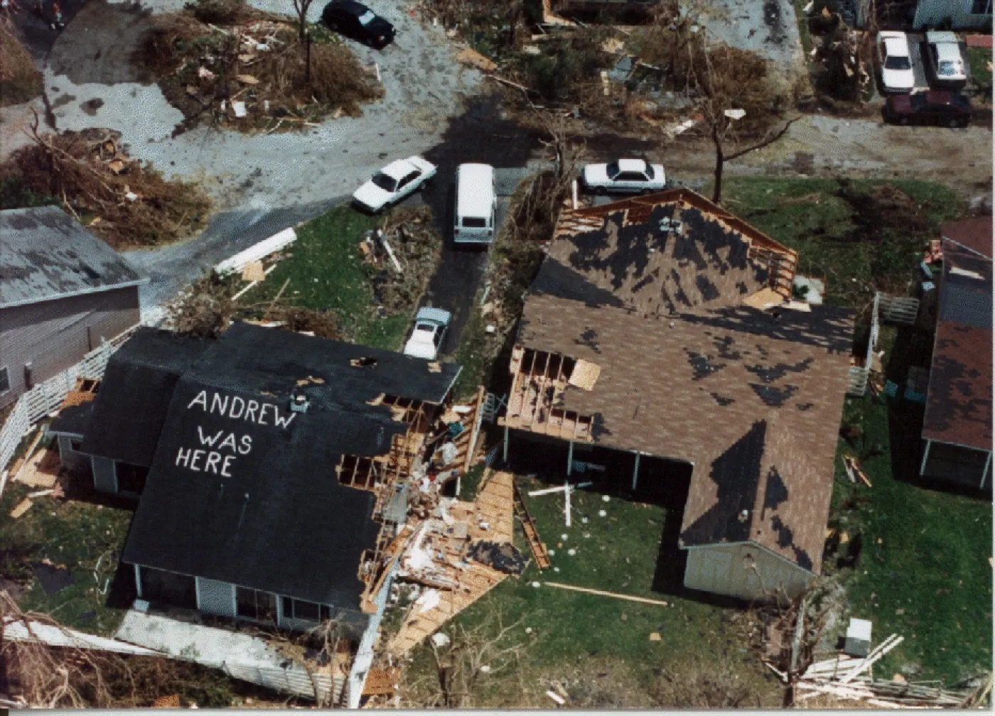 Aerial view of damaged homes with ANDREW WAS HERE spray-painted on a roof