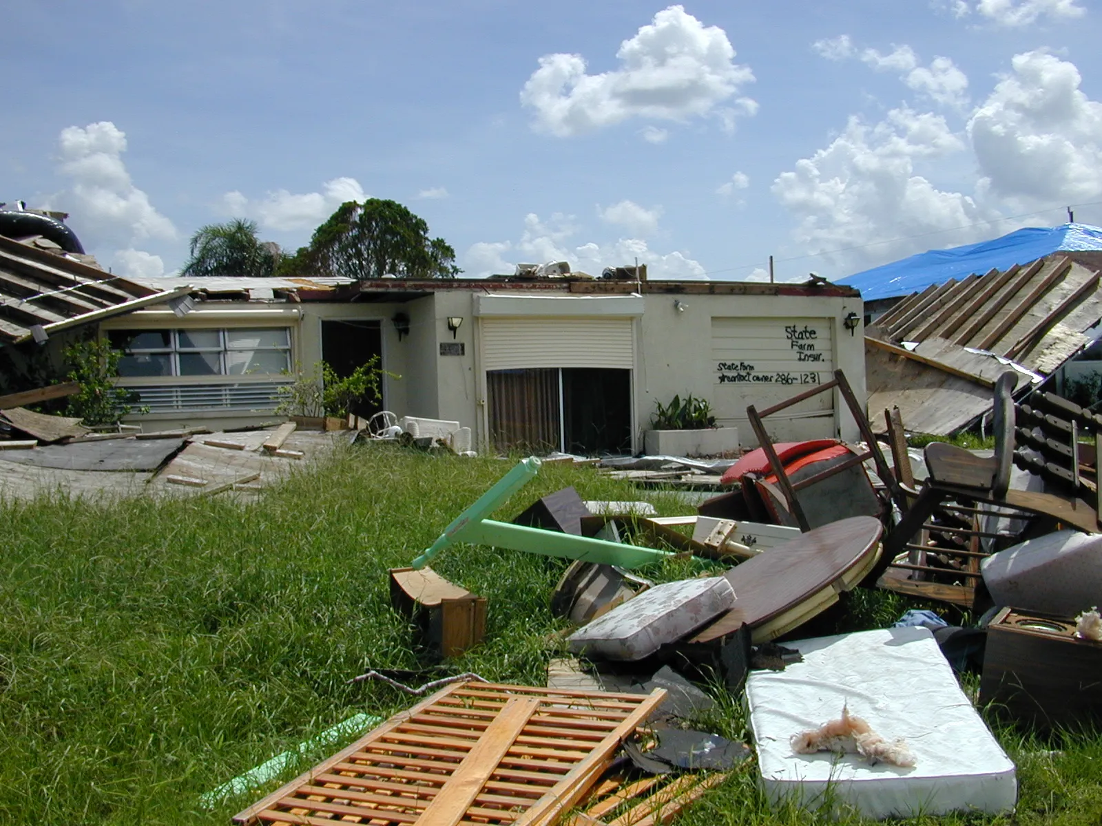 A Punta Gorda home with its roof torn off and belongings strewn across the yard after Hurricane Charley