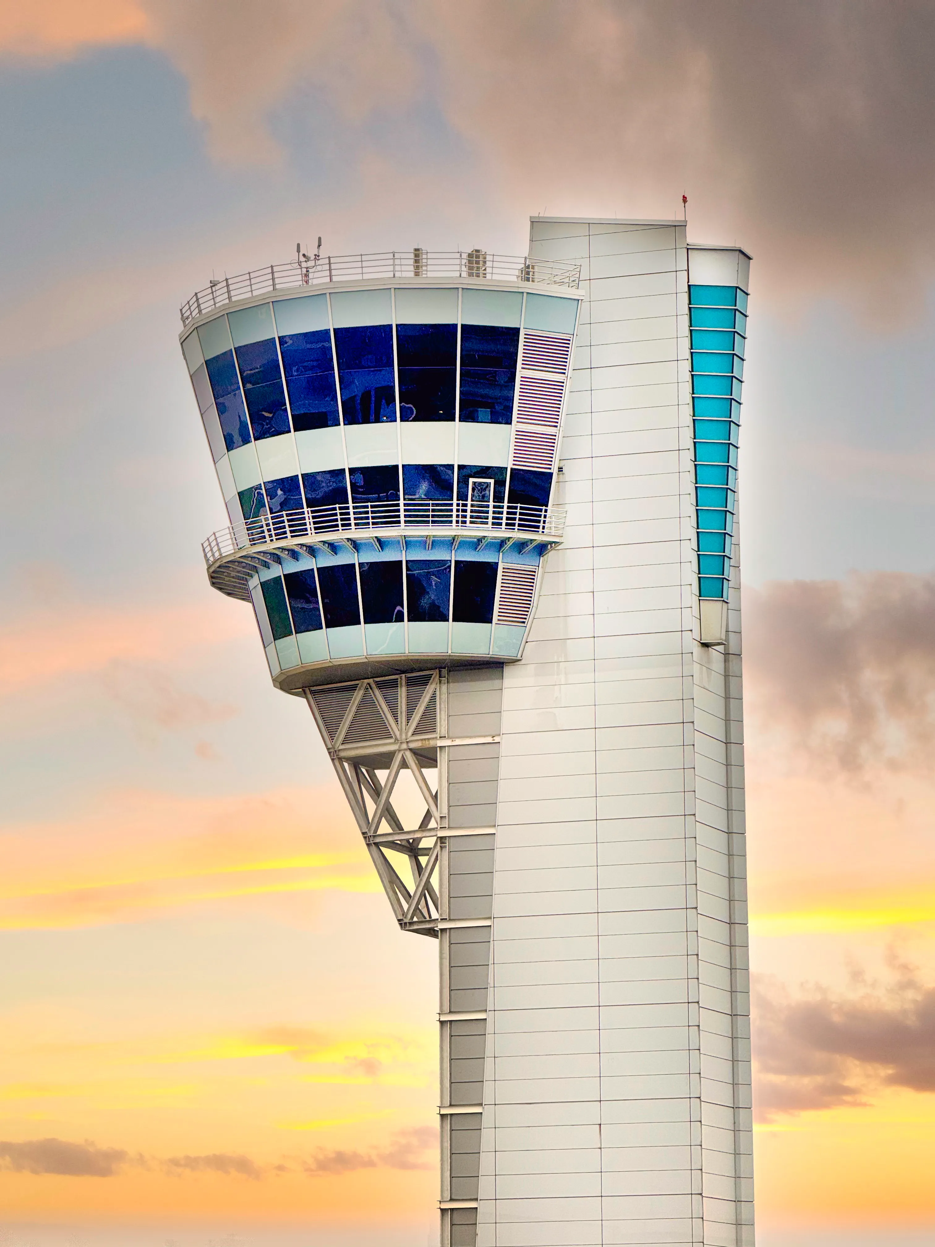 An FAA air traffic control tower silhouetted against a dramatic sky at dusk