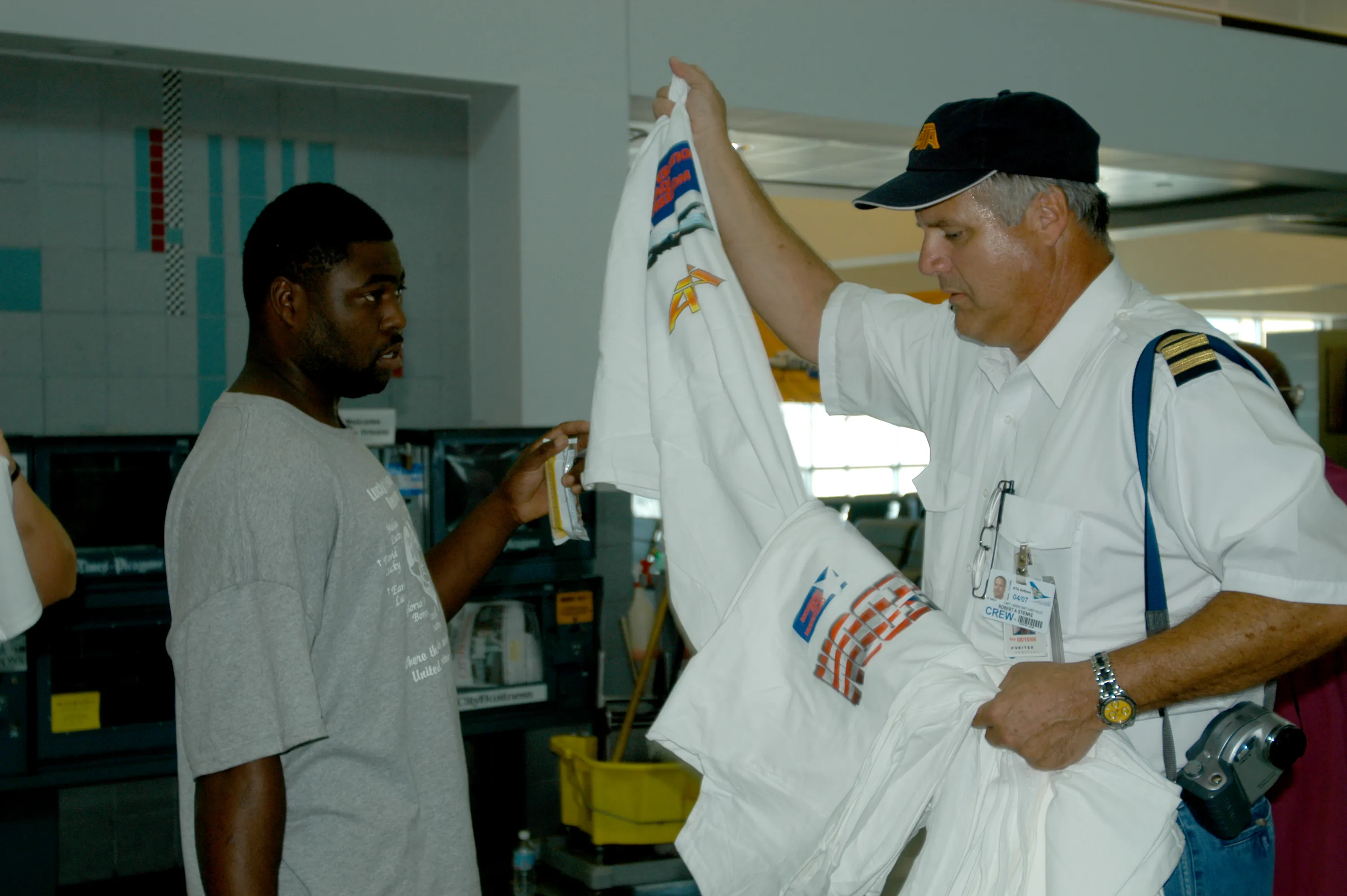 A relief worker hands out clothing to an evacuee inside an airport terminal after Hurricane Katrina