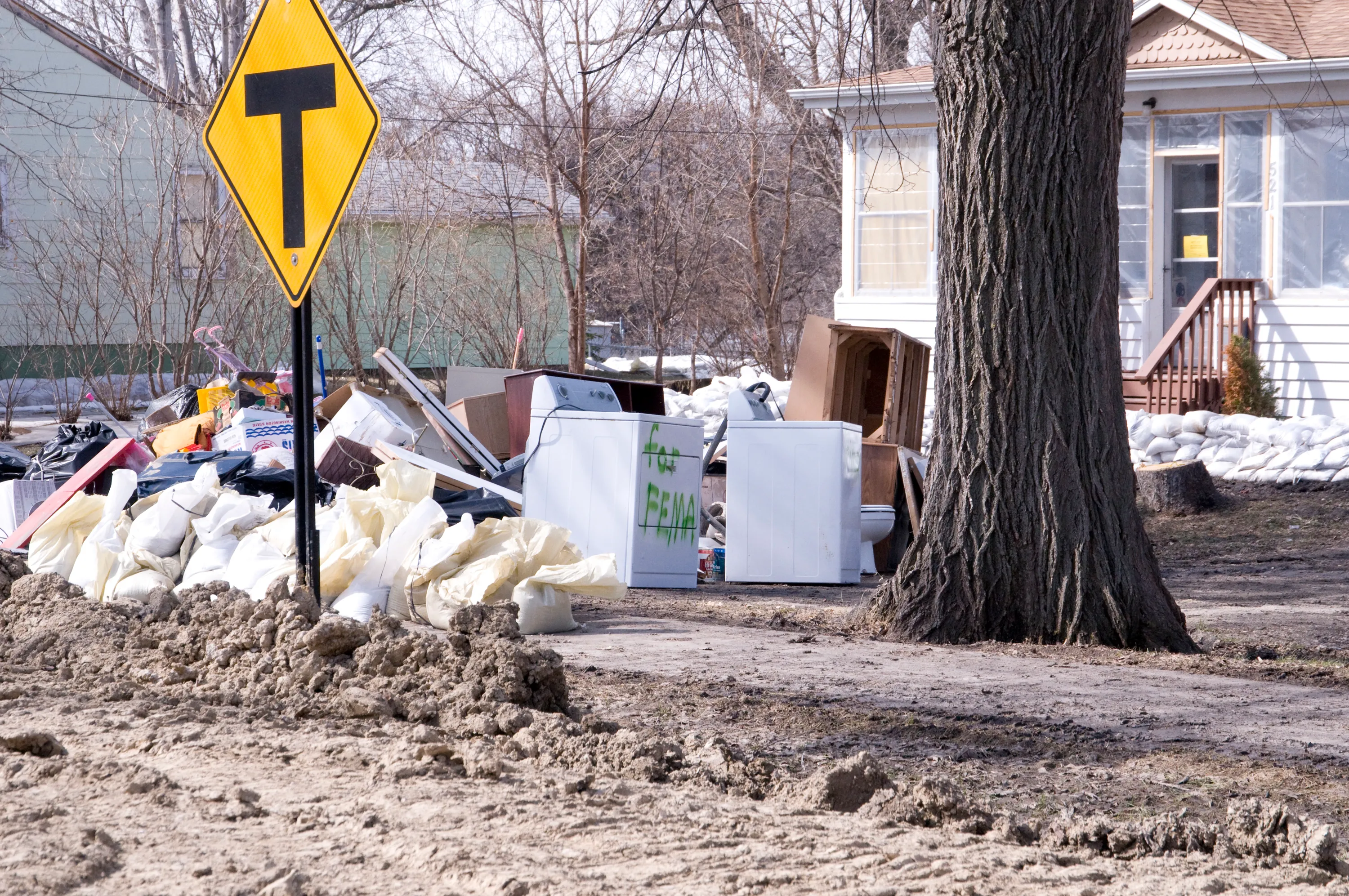 Ruined appliances and water-damaged contents piled at the curb after a flood