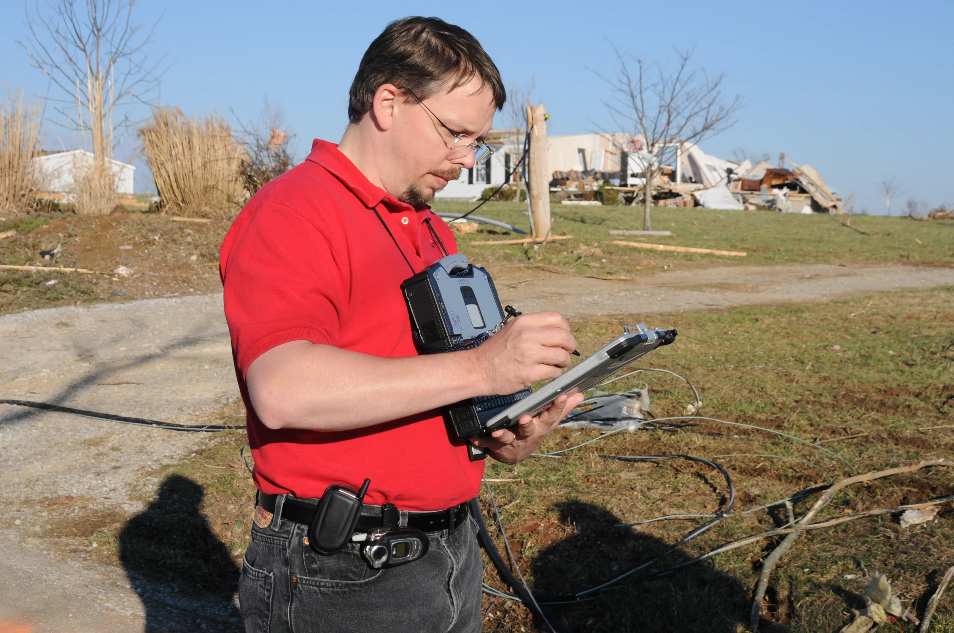 A damage assessor records the condition of a storm-destroyed home on a rugged tablet
