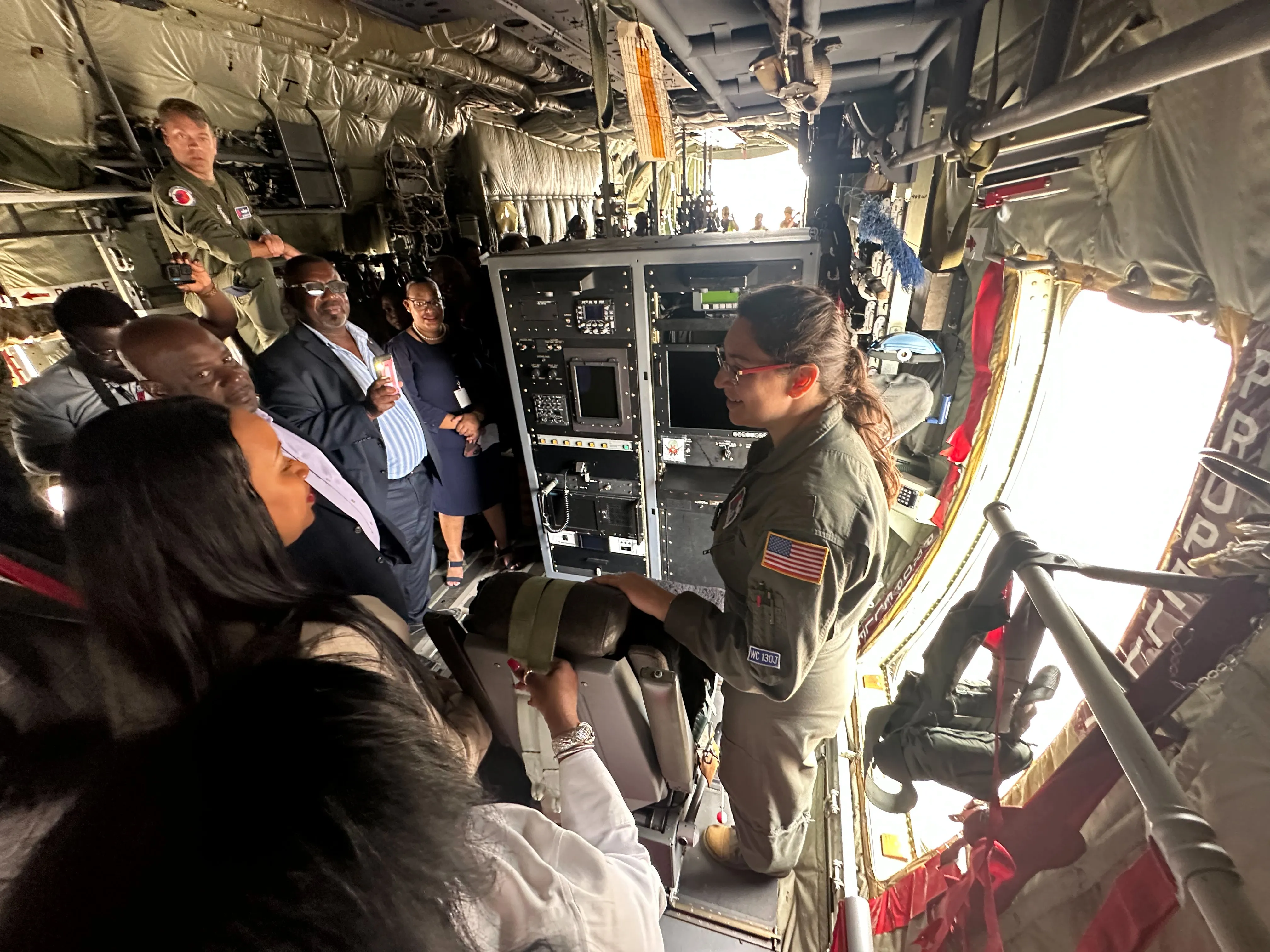 A Hurricane Hunter crew member shows the weather-officer console inside a WC-130J to visitors during an outreach tour