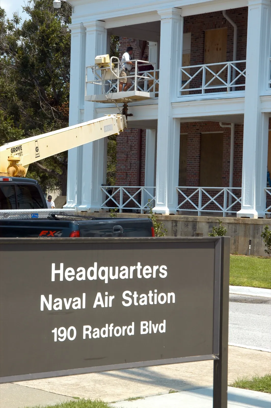 A worker installing plywood over building windows ahead of a hurricane