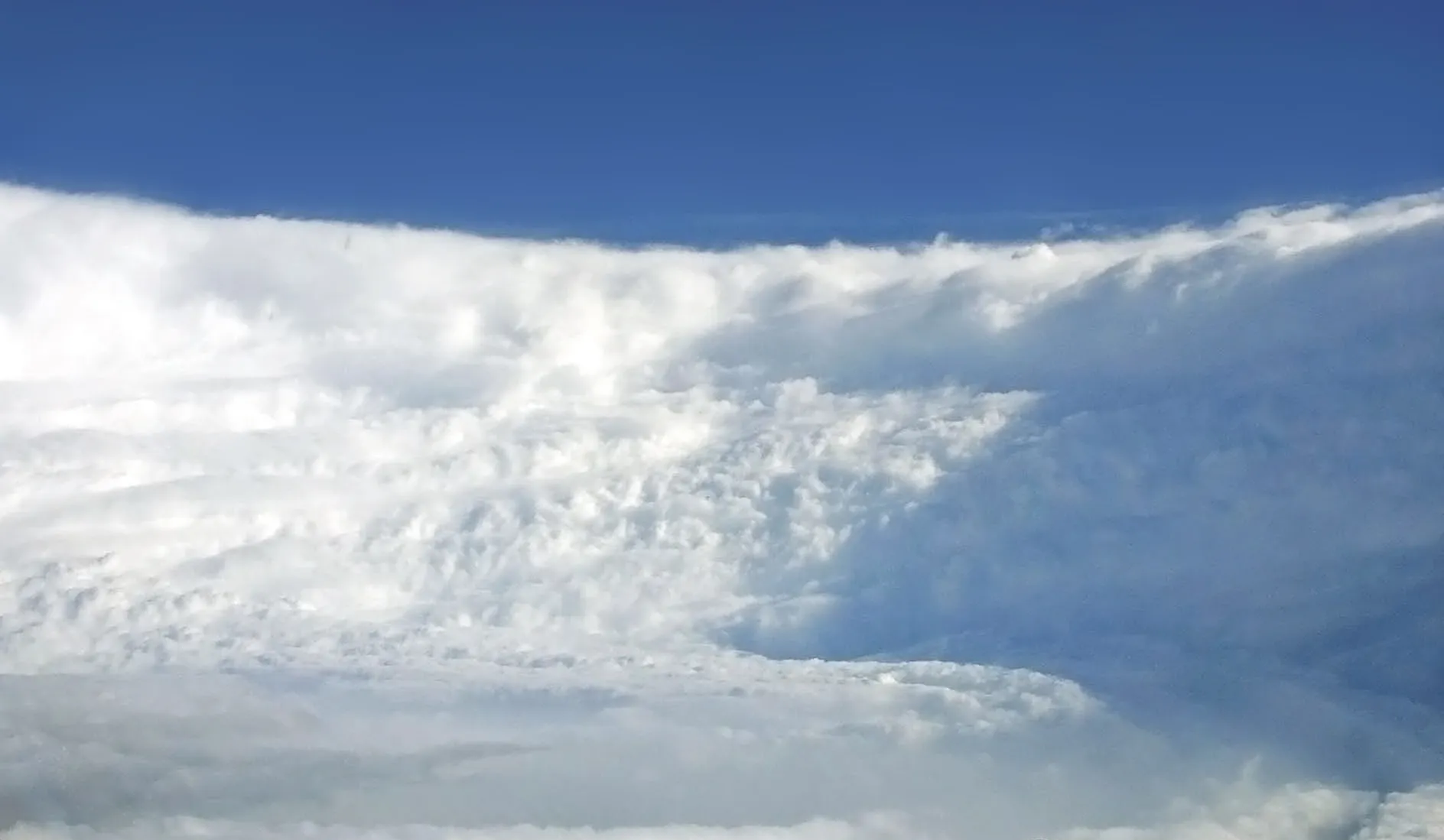 The view from inside a hurricane's eye, looking out at the towering wall of cloud surrounding clear blue sky, the stadium effect