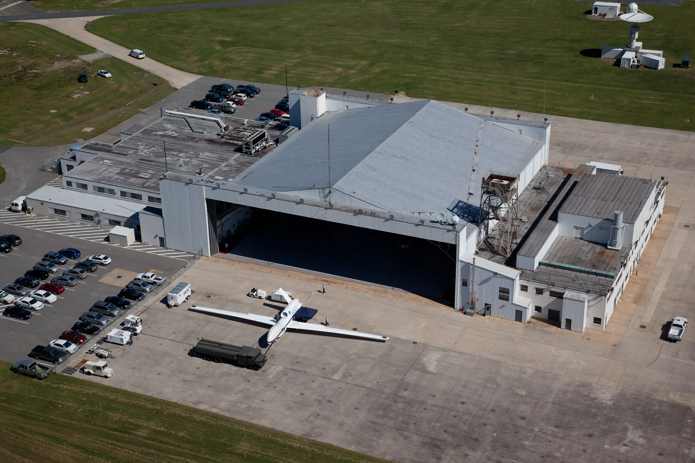 Aerial view of a Northrop Grumman Global Hawk uncrewed aircraft on the ramp outside its hangar