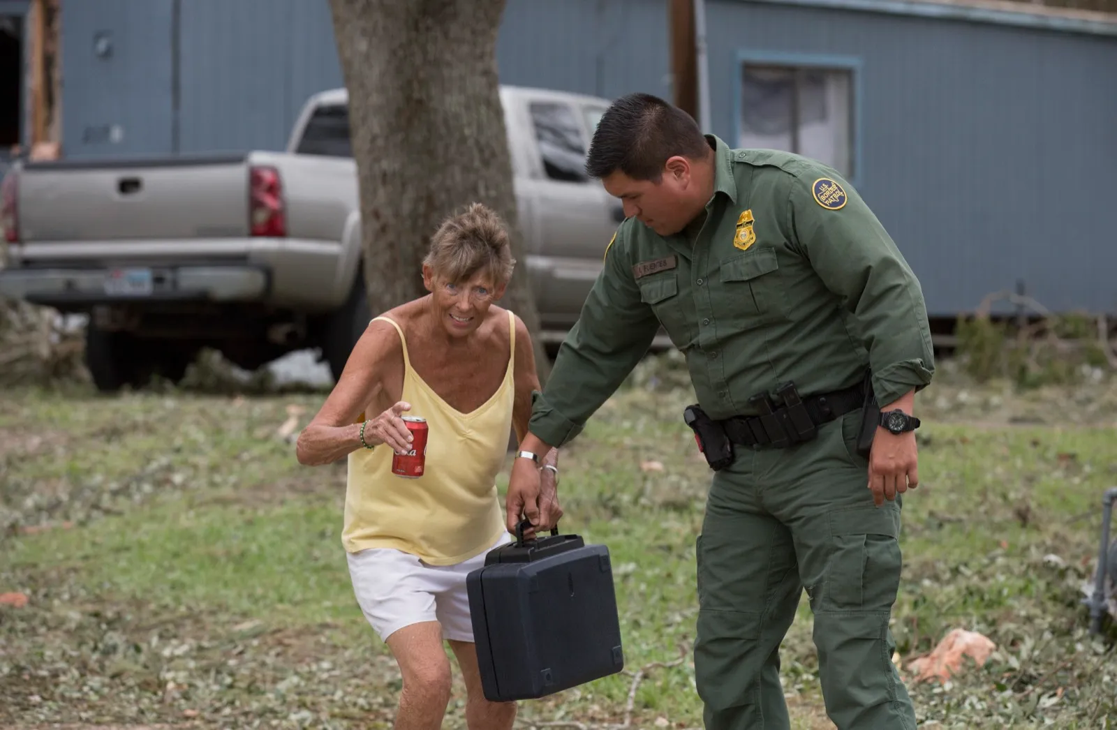A Customs and Border Protection agent helps an elderly resident through storm debris after Hurricane Harvey