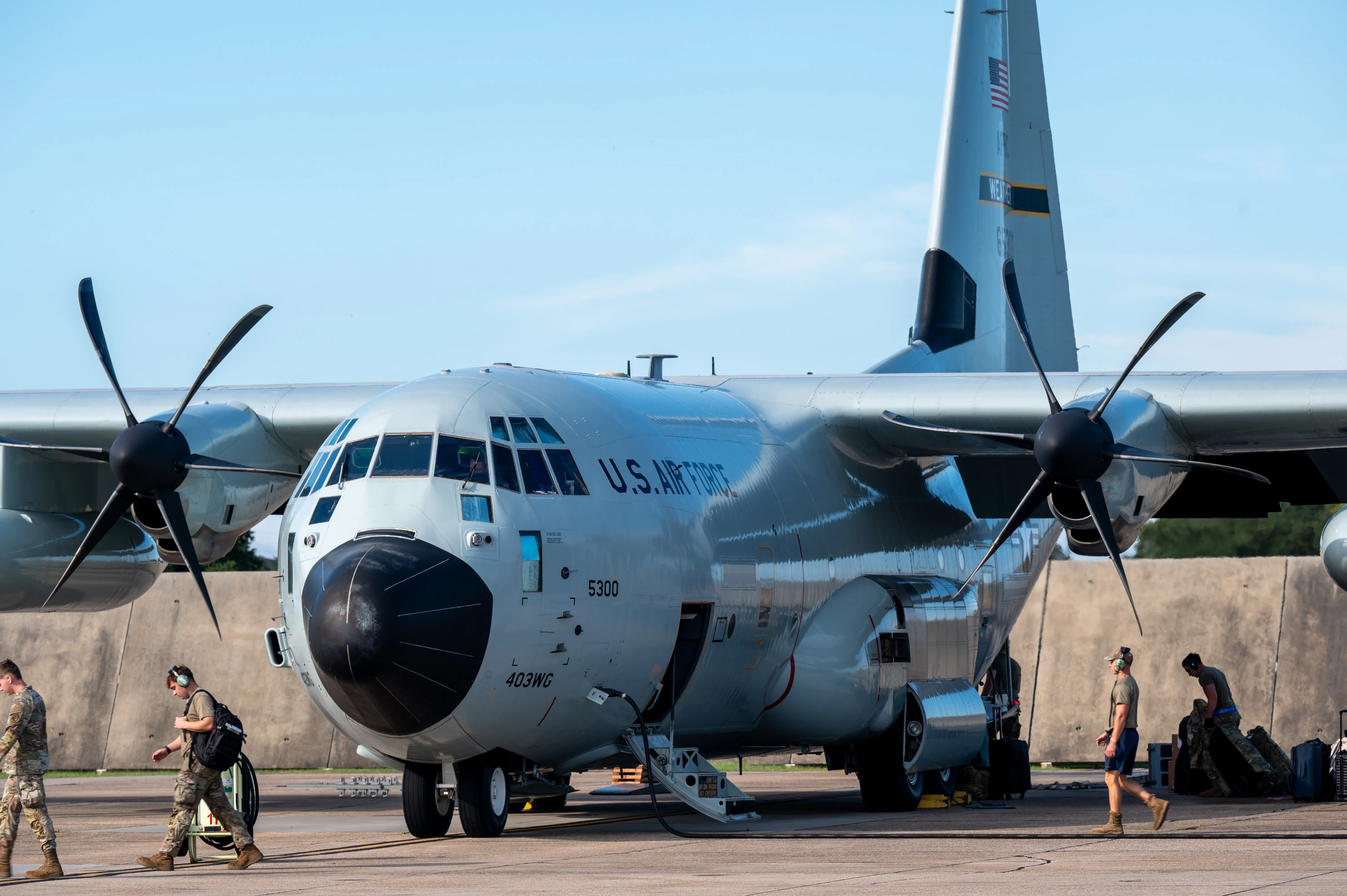 Aircrew work inside the cargo bay of a C-130 near the rear ramp