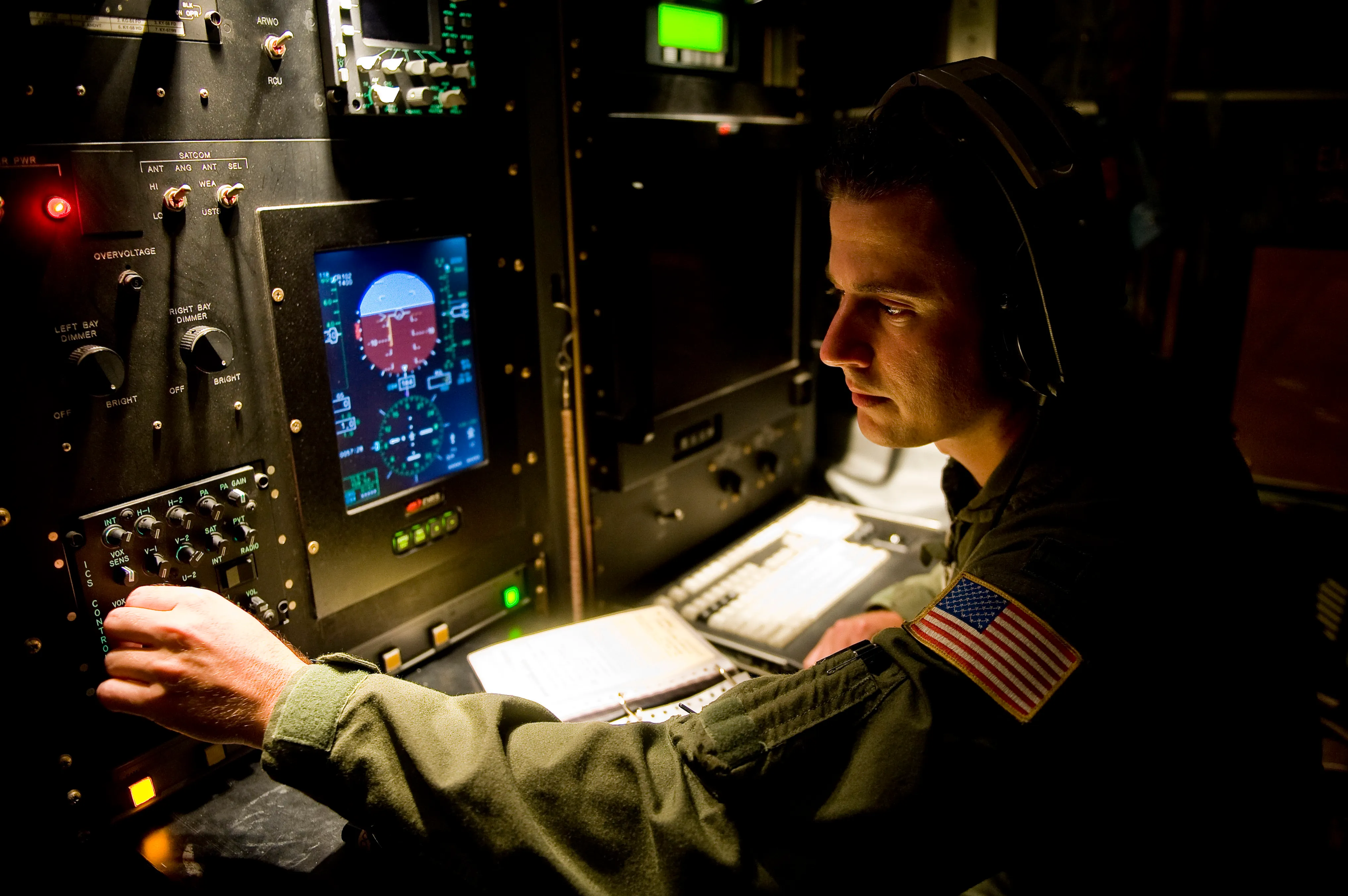 A weather officer concentrates on instrument and radar displays at a console during a hurricane flight