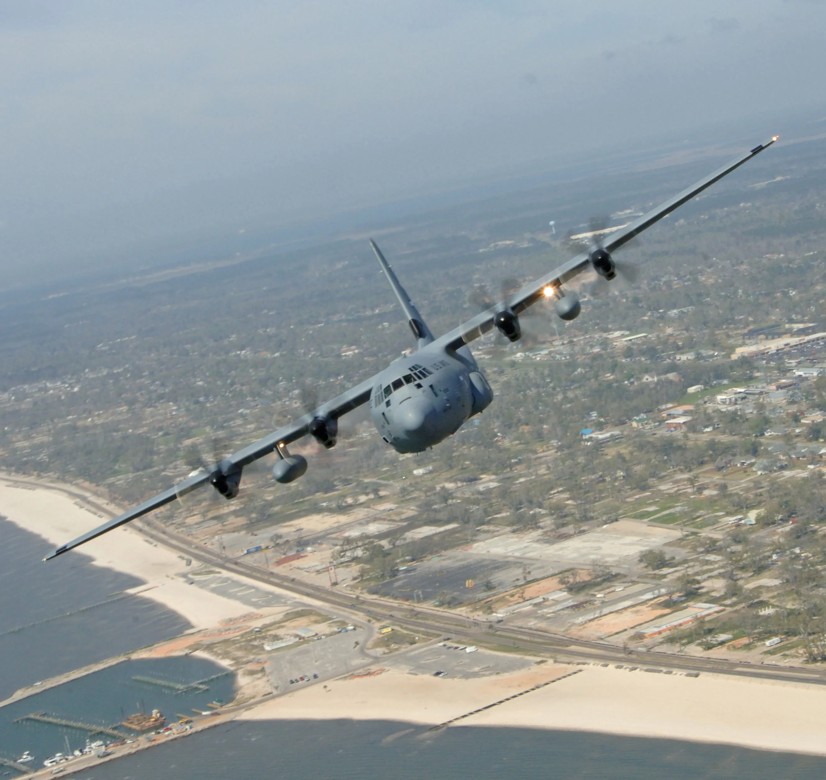 An Air Force Reserve WC-130J "Hurricane Hunter" banks over a storm-battered coastline