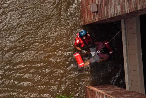 A U.S. Coast Guard rescue swimmer pulls a pregnant woman from her flooded New Orleans home