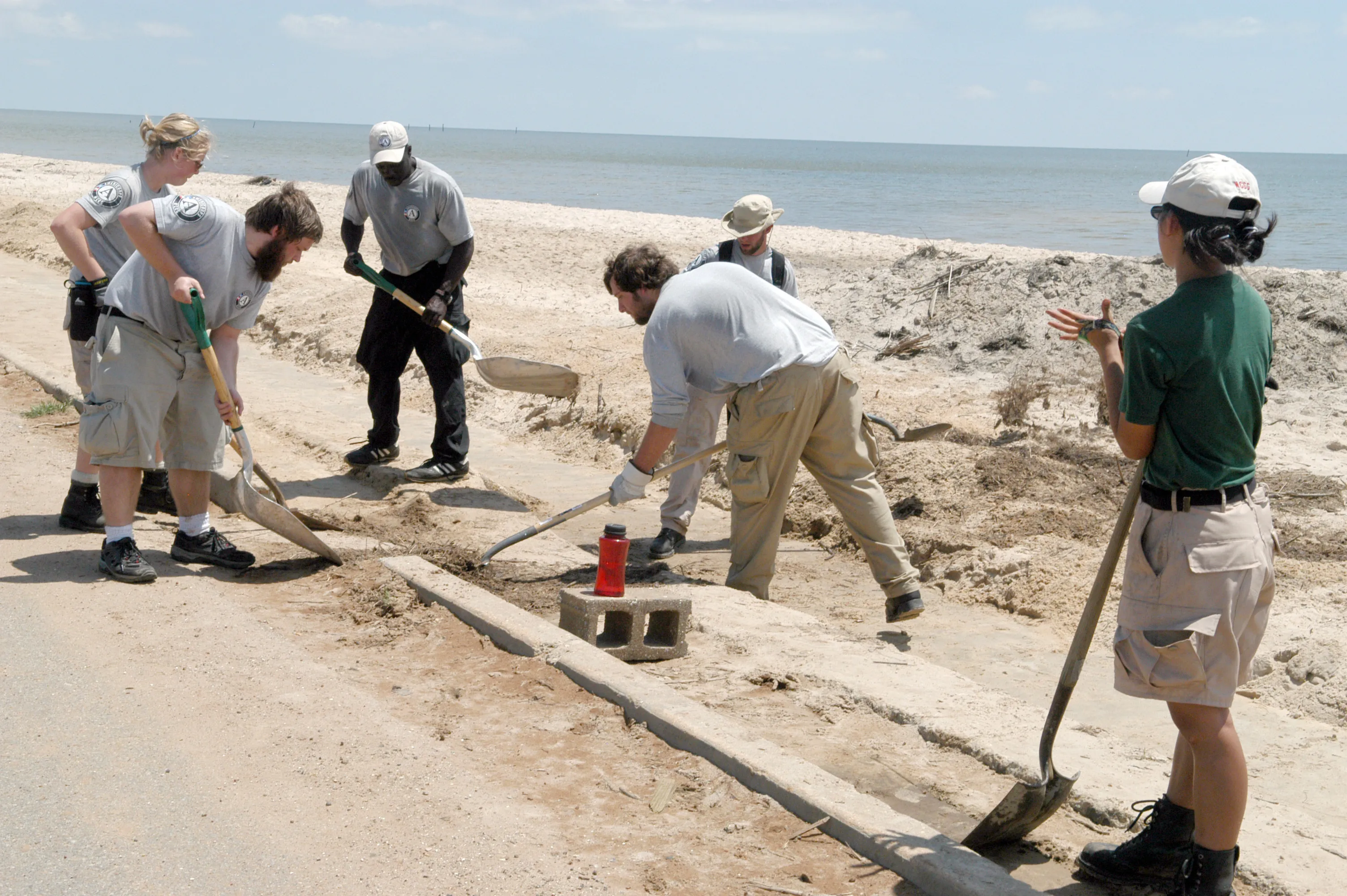 Cleanup crews shovel storm debris from a road after a hurricane