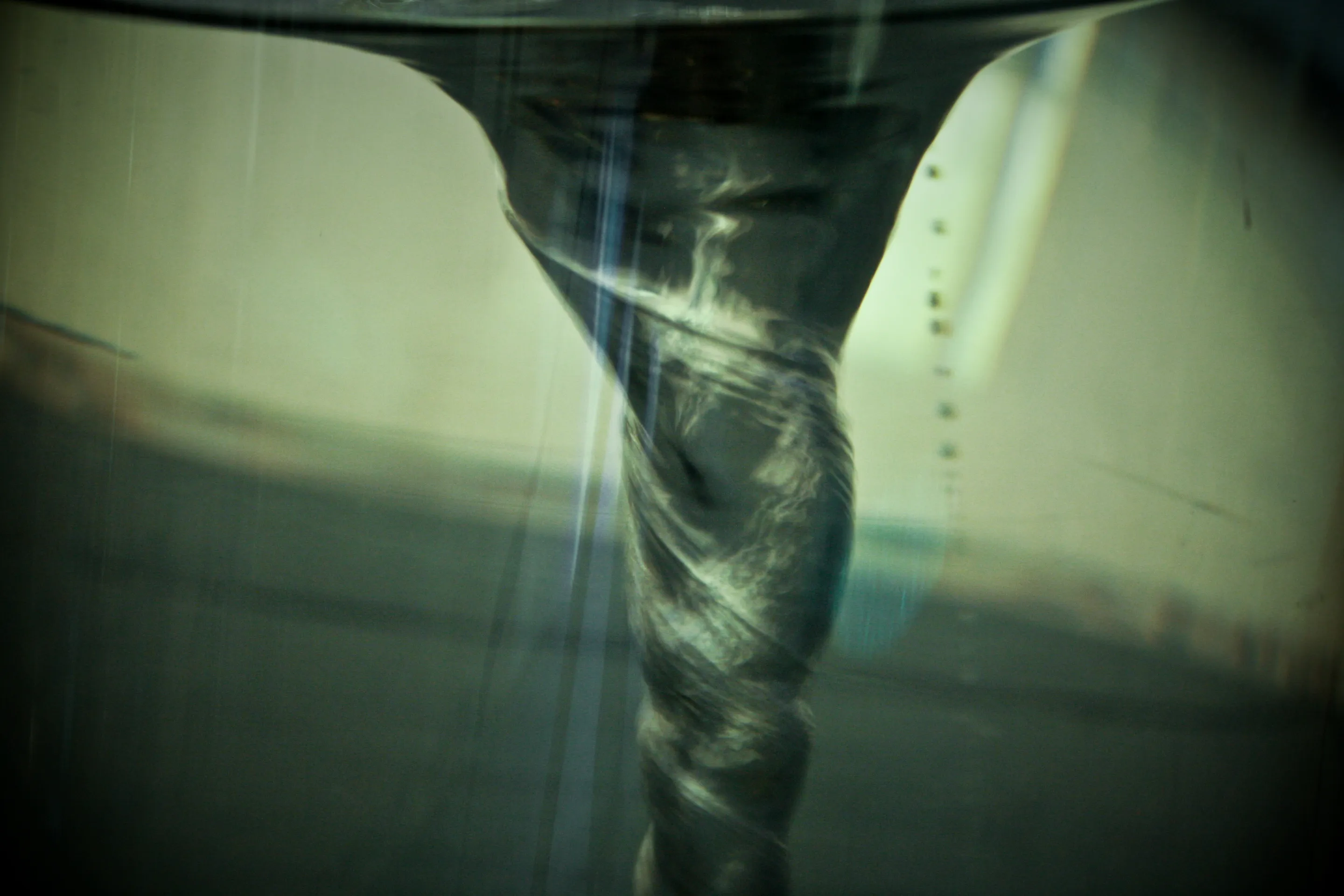 A swirling vortex of water forms a funnel shape in a clear container