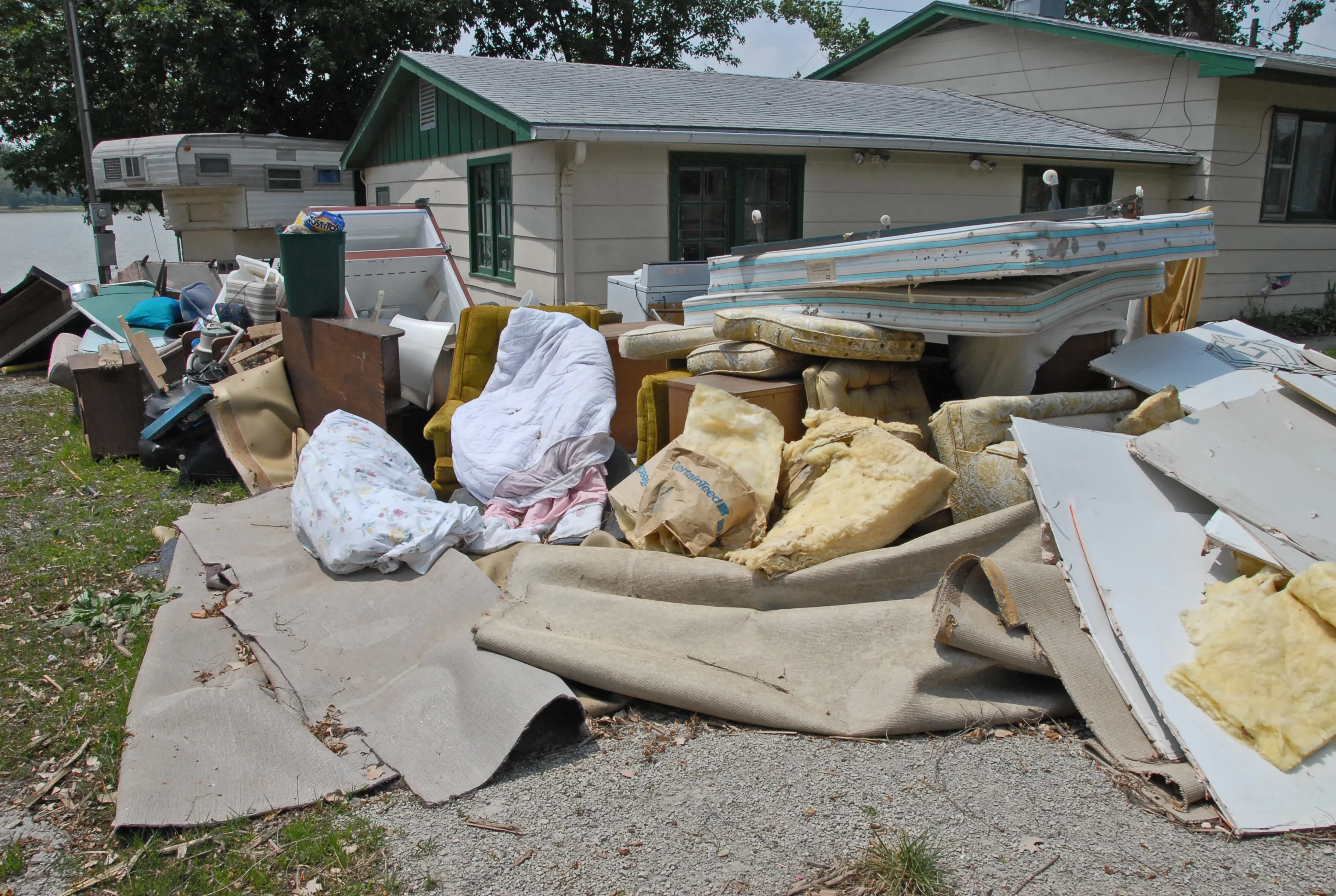 Ruined furniture, mattresses, and household contents piled outside a flood-damaged home