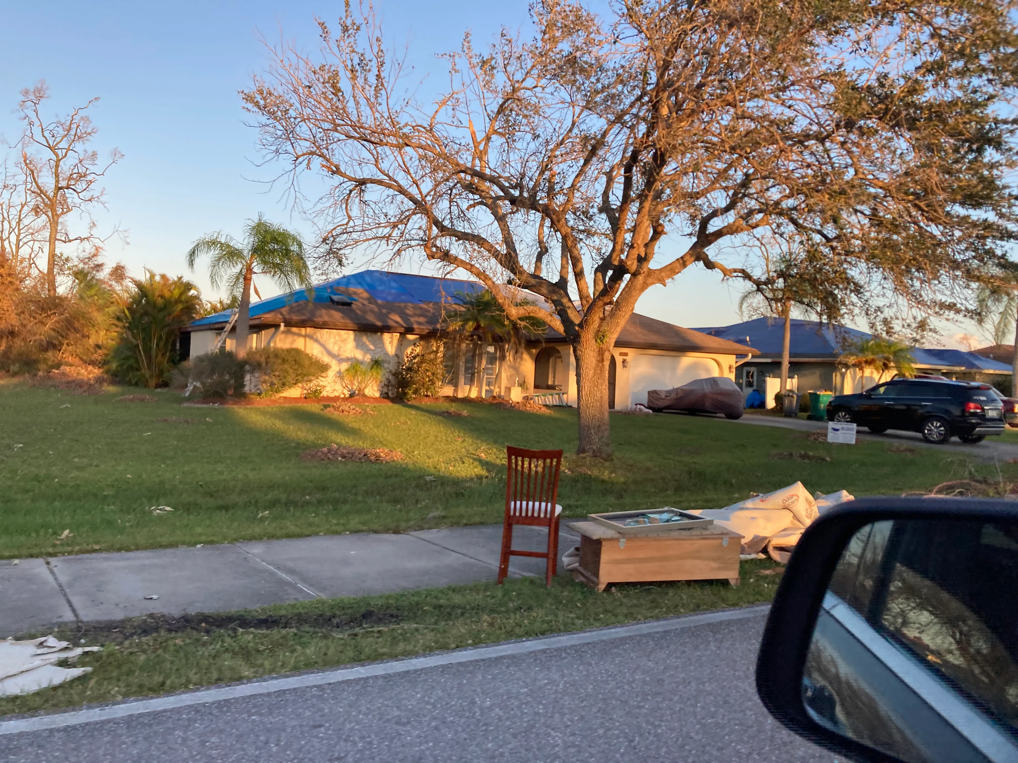 A blue tarp covers the storm-damaged roof of a single-family home after Hurricane Ian