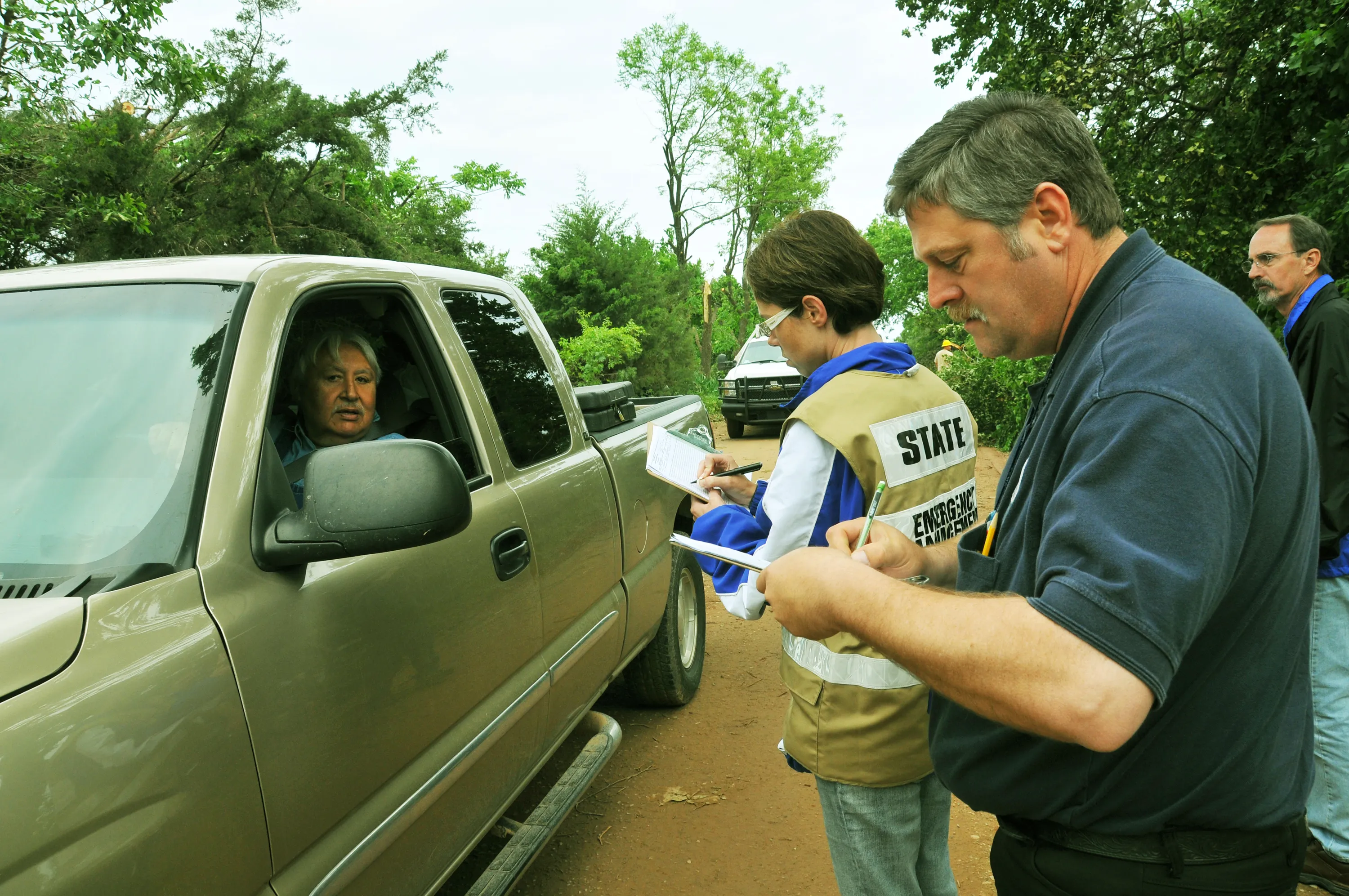 Emergency-management staff interview a resident and take notes during a post-storm assessment