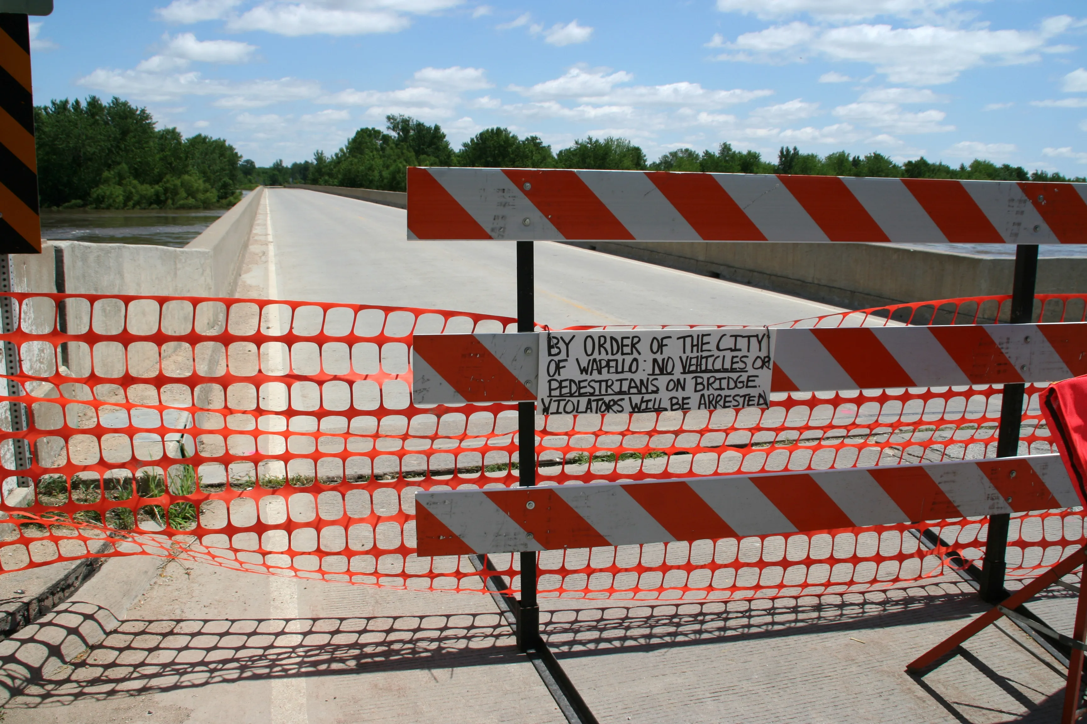 A road closed by a barricade where floodwater has covered the pavement ahead
