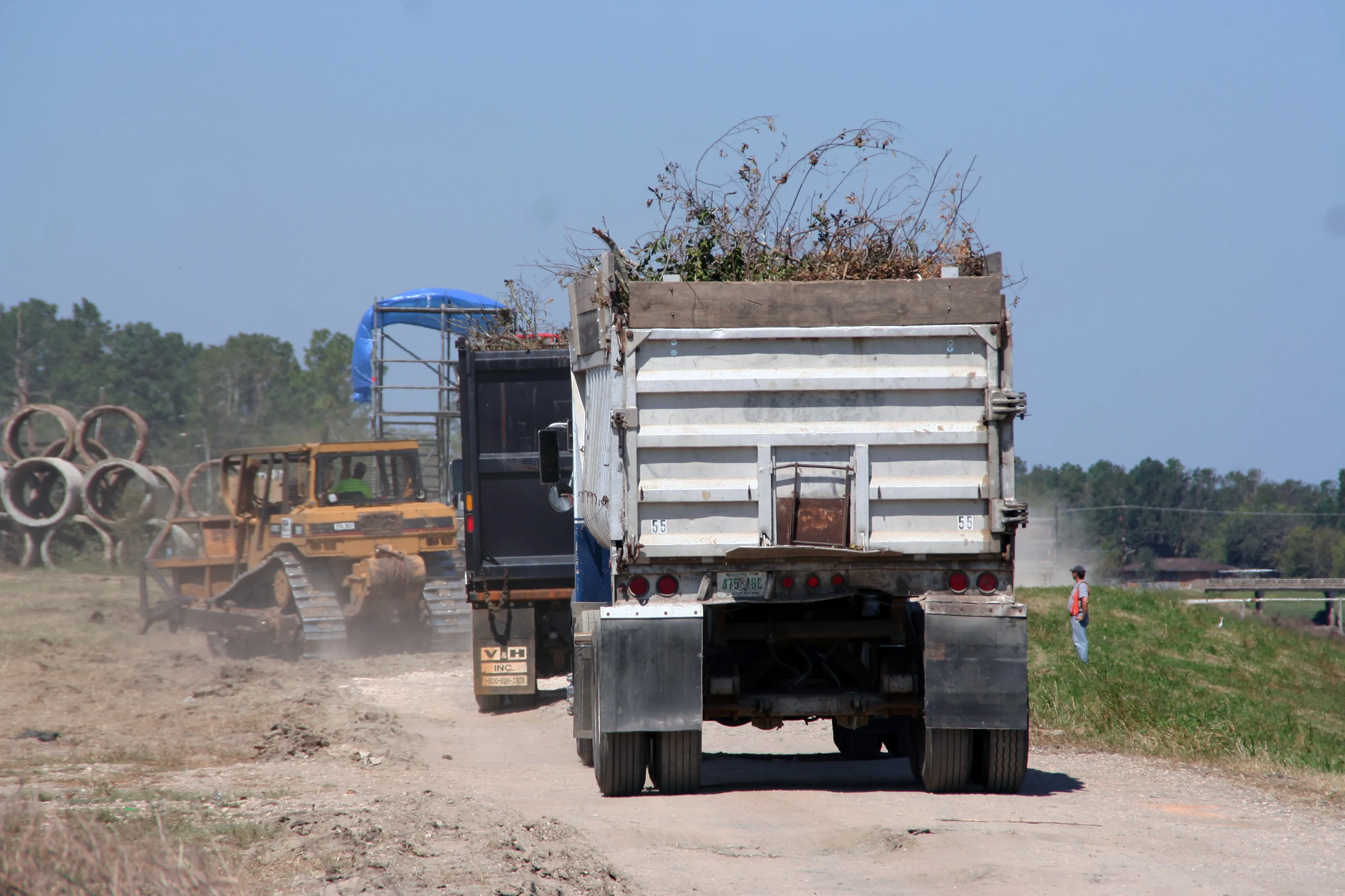 A convoy of trucks hauling away mountains of hurricane debris