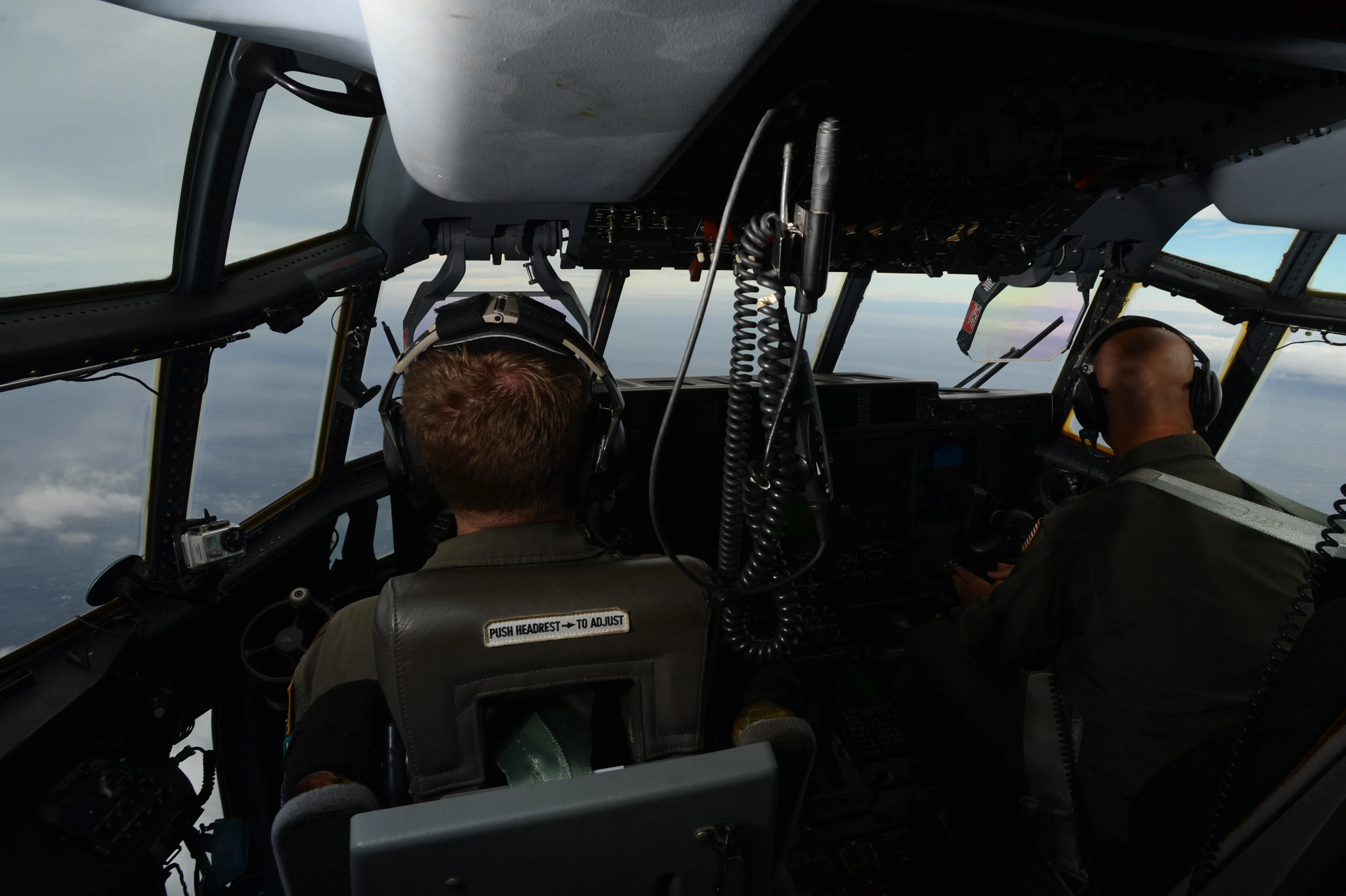 Two Hurricane Hunter pilots seen from behind in the cockpit of a WC-130J during a reconnaissance flight