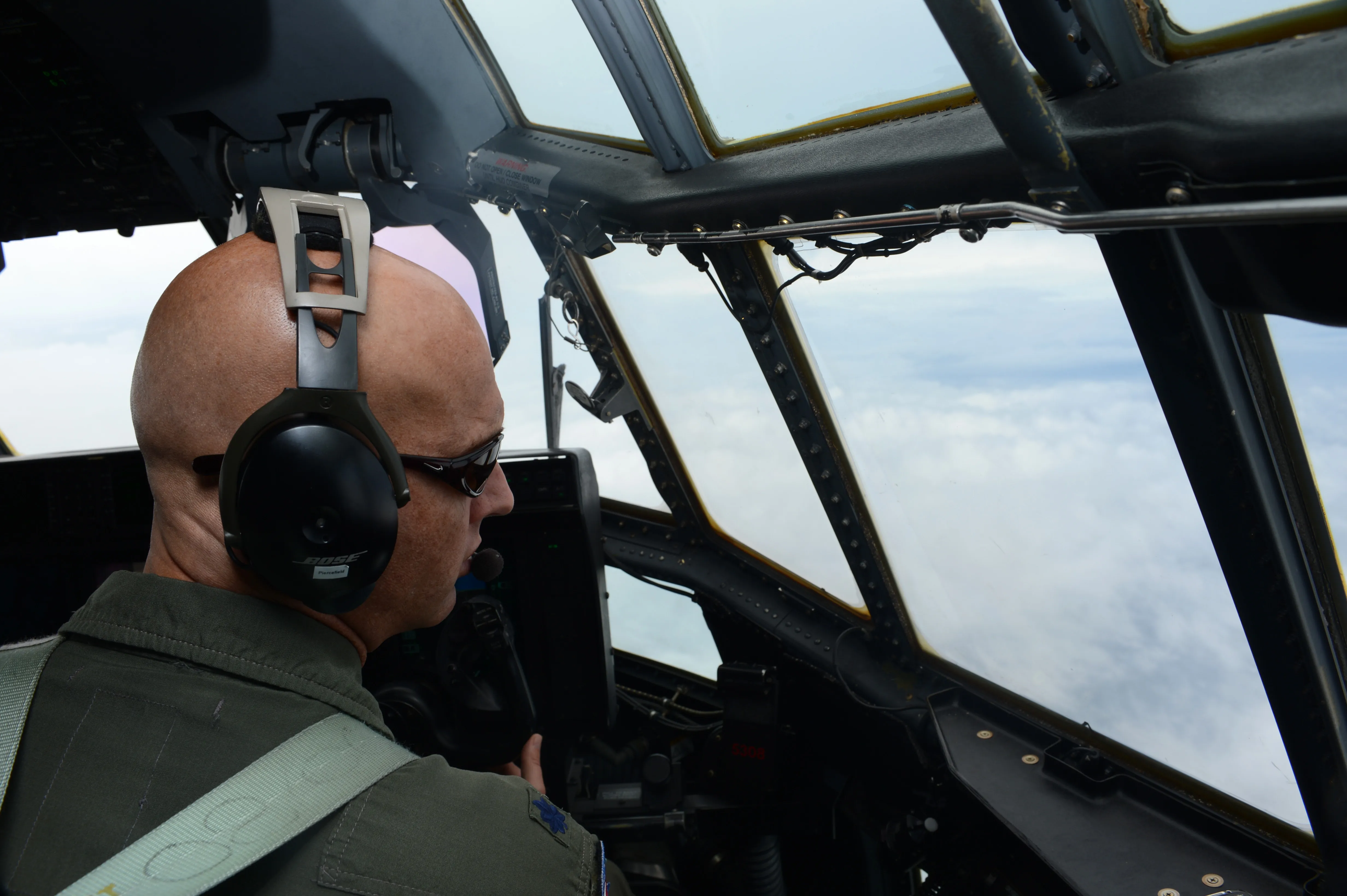 A Hurricane Hunter pilot looks out from the flight deck of a WC-130J during a storm reconnaissance flight