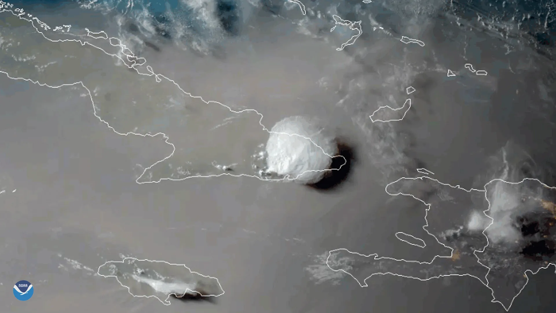 A satellite image of a tropical storm near Cuba being overtaken by a tan-colored mass of dry, dusty Saharan air