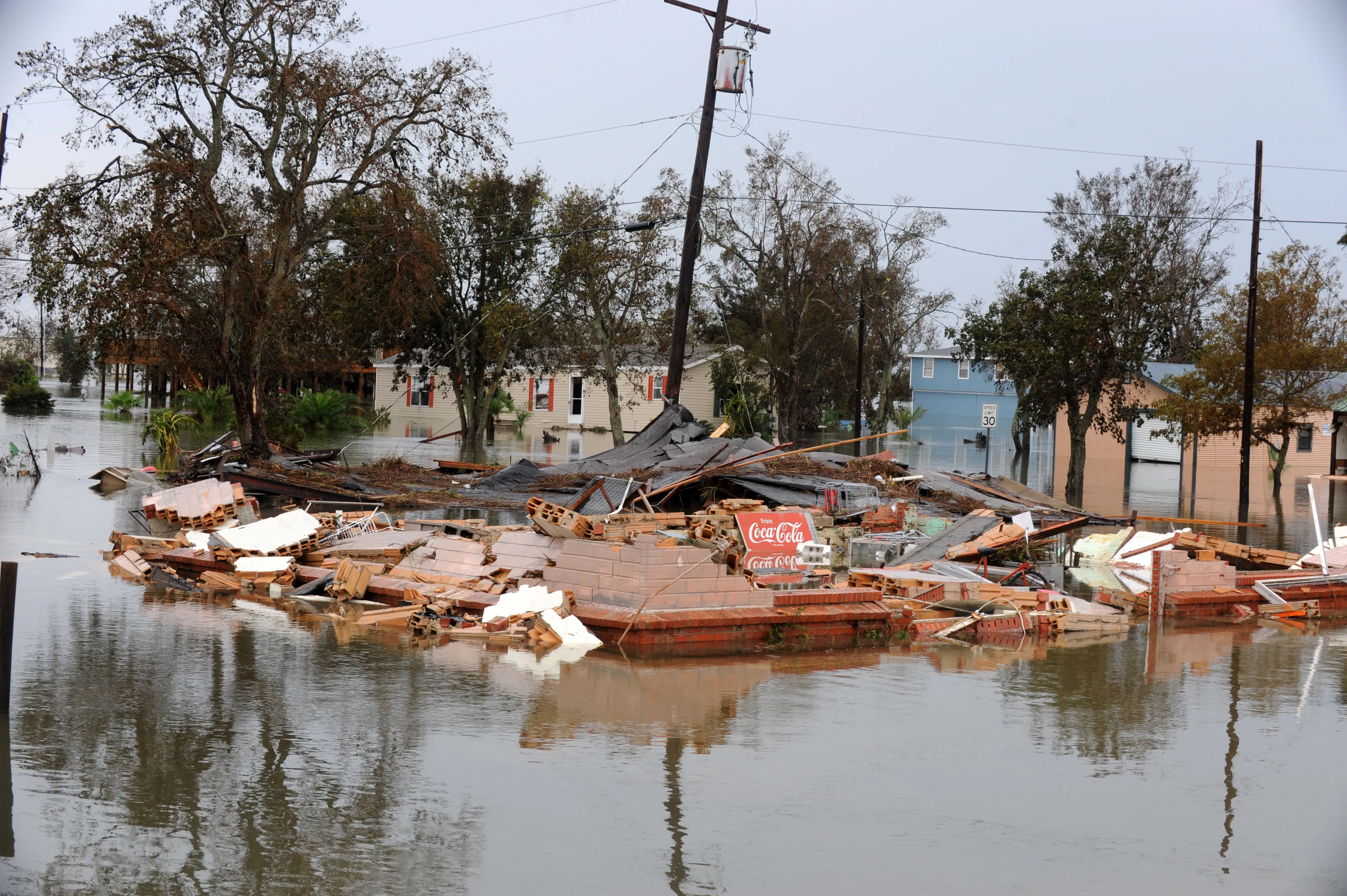 A house collapsed into a pile of debris sitting in standing floodwater after a hurricane