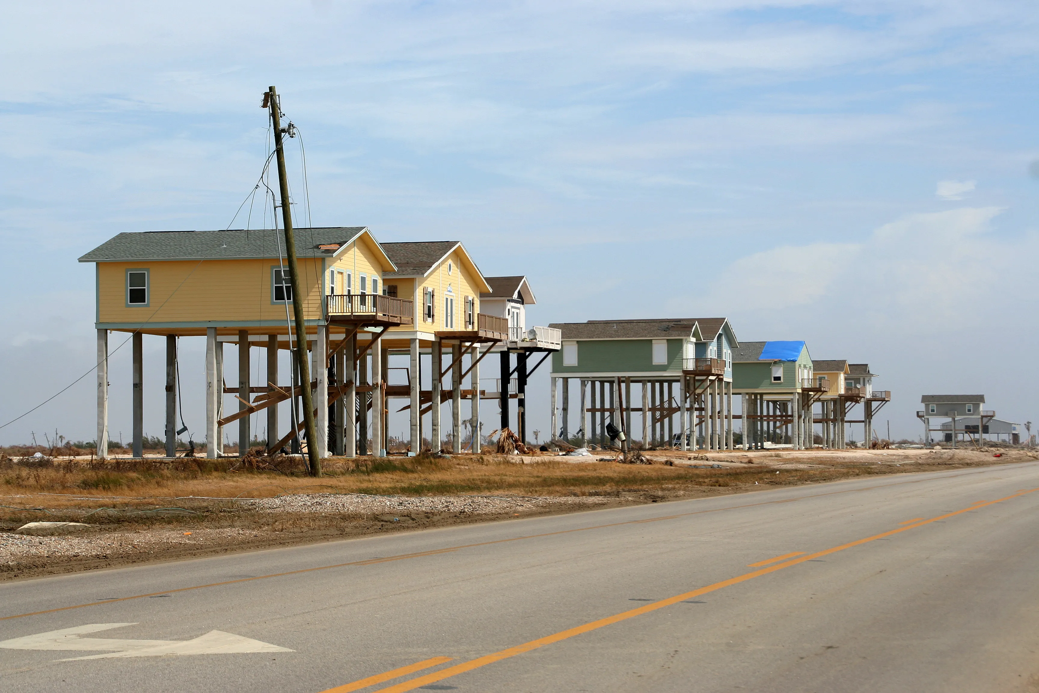 A row of large homes on stilts lining a low Texas barrier-island coast