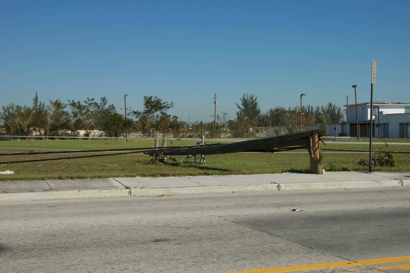 A snapped utility pole and downed power lines along a road in the Miami area after Hurricane Wilma
